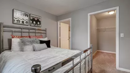 A bedroom featuring a walk-in closet and simple, clean furnishings.