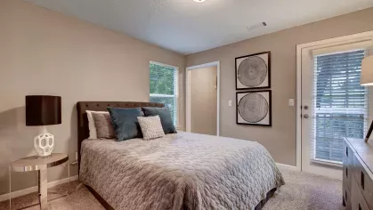 A tranquil bedroom with a soft-toned bedspread, stylish decor, and access to a patio.