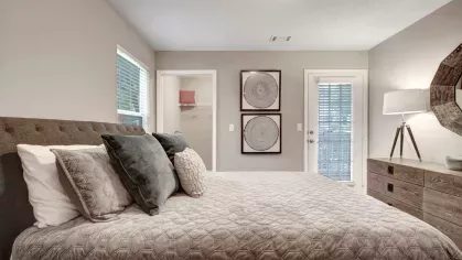 A cozy bedroom featuring neutral tones, decorative wall art, and a private balcony entrance.
