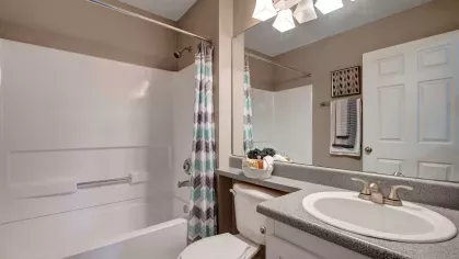 A bathroom with a bathtub, patterned shower curtain, and ample vanity space under soft lighting.