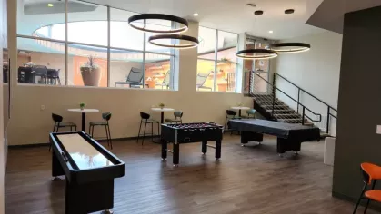 A game room featuring shuffleboard, foosball, and billiards with bright, modern decor.