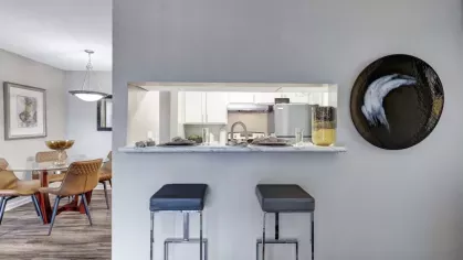 A chic breakfast bar with marble-style countertops, two sleek barstools, and a view into the kitchen, complemented by stylish wall art and decor.