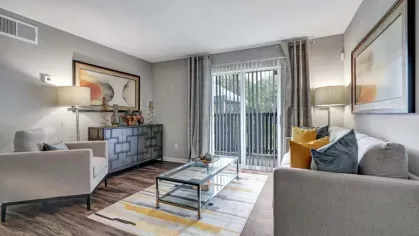 Another view of the living room, showcasing contemporary decor, a media console, and a rug with yellow, gray, and white accents.