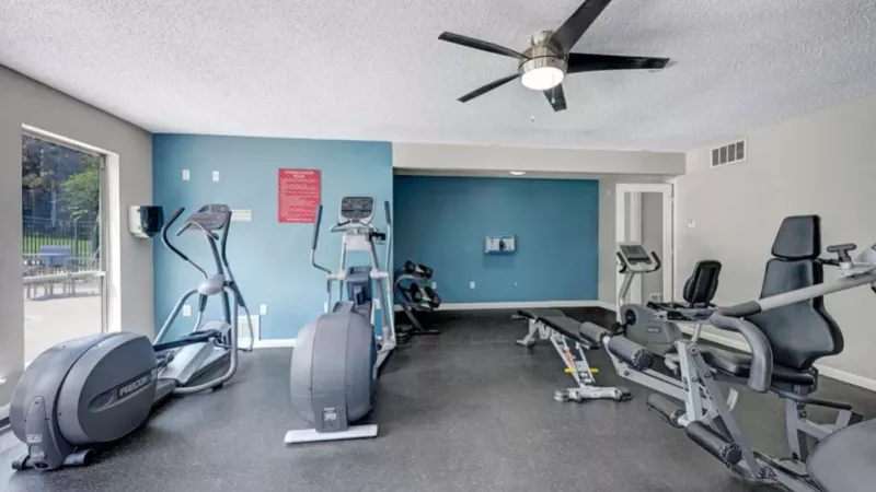 A gym with exercise machines, weights, and a blue accent wall, designed for a variety of workouts.