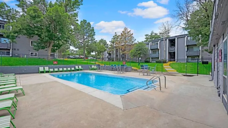 Another angle of the outdoor pool showcasing seating options and landscaped areas with apartment buildings in the background.