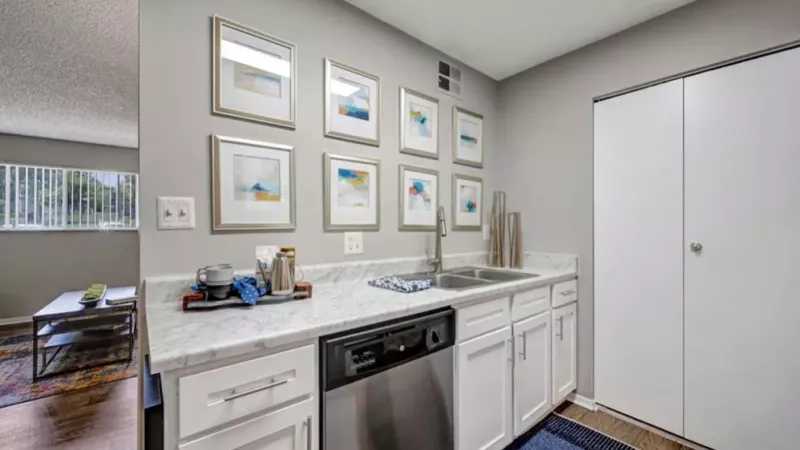 A stylish kitchen showcasing white cabinetry, a marble countertop, and decorative wall art.