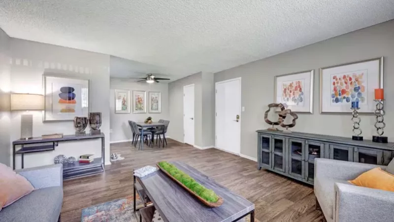 A spacious living room with contemporary furniture, decorative accents, and large windows providing natural light.