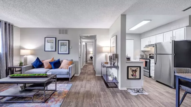 An open-concept apartment layout displaying a vibrant living room, a dining area, and a well-equipped kitchen.