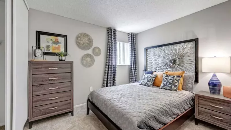 A modern bedroom featuring a decorative headboard, neutral bedding, and accent pieces for a cozy ambiance.