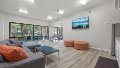 A spacious common room with modern decor, a large TV, and comfortable seating arrangements for social gatherings.