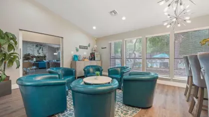 A cozy seating area with teal armchairs arranged around a small circular table in a modern lounge space.