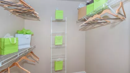 A spacious walk-in closet with multiple wire shelves holding gift bags and wooden hangers for ample storage.
