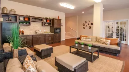 A cozy clubhouse living area featuring leather armchairs, a stone fireplace, and inviting warm colors.
