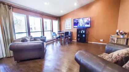 A cozy living room with leather seating, a dining table, and a mounted TV.
