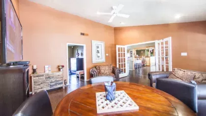 A meeting room with a round wooden table and inviting leather armchairs under soft lighting.