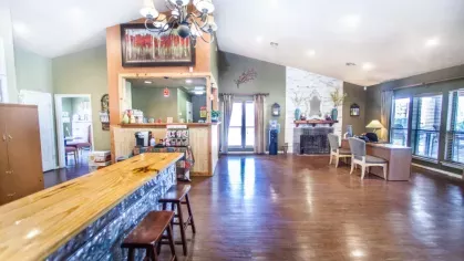 A spacious clubhouse with a bar, fireplace, and ample seating, exuding a warm and rustic ambiance.