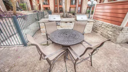 A round table with chairs near a stone grill station in a cozy outdoor patio setting.