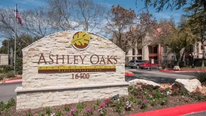 The main entrance sign for Ashley Oaks Apartment Homes, displaying the address 16400 in a landscaped setting.