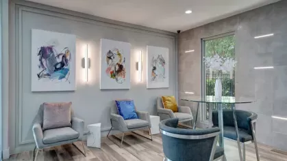A cozy lounge area with modern armchairs, a glass table, and vibrant artwork on the walls, creating a comfortable space for relaxation.