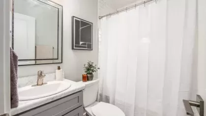 A contemporary bathroom with a clean design, including a white shower curtain, marble countertop, and minimalistic decor.