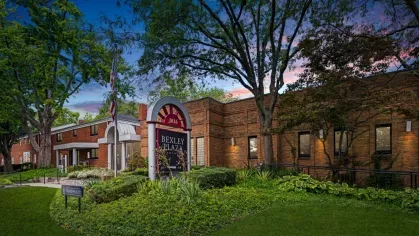 A twilight shot of Bexley Plaza’s entrance sign surrounded by greenery and illuminated by soft lighting.