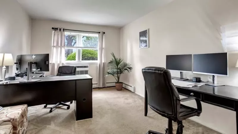 A private office setup featuring a desk, computer monitors, and a window with natural light illuminating the space.