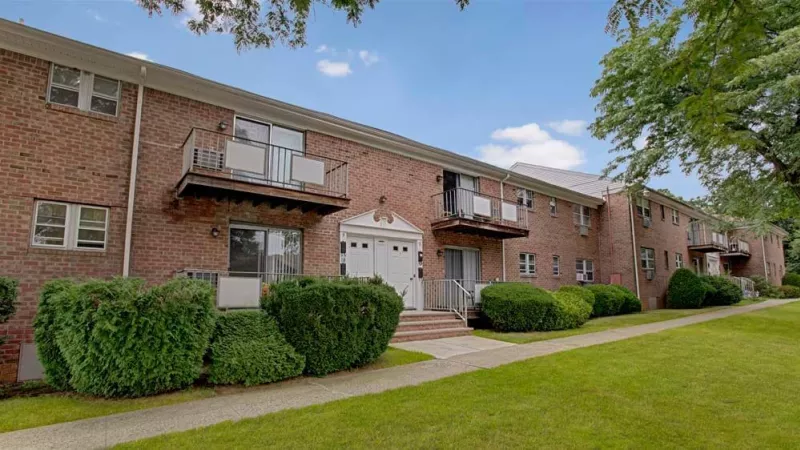 A detailed shot of an apartment entrance with red accents and a leasing office sign in front.
