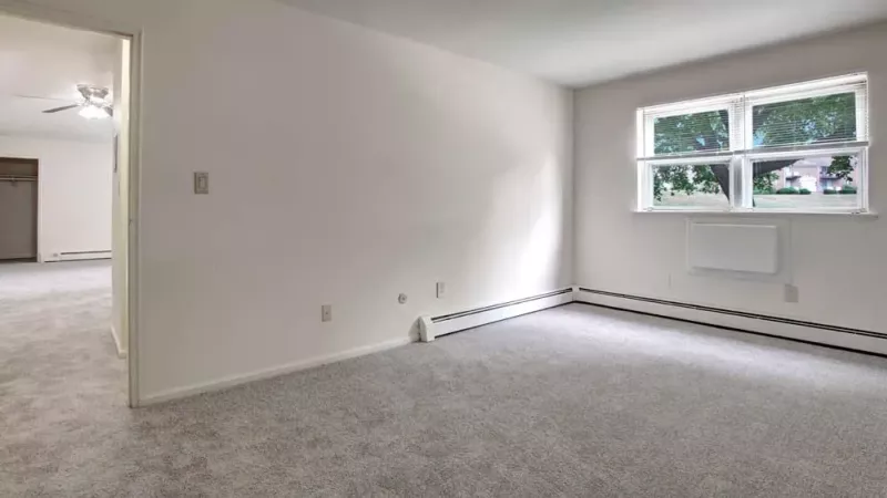 A spacious bedroom with neutral carpet, large windows, and ample natural light.