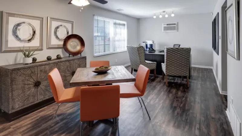 A spacious dining and office area with contemporary decor and orange dining chairs.