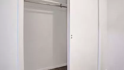 A simple closet with sliding white doors and a hanging rod for storage.