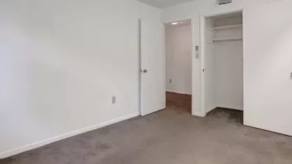 A carpeted bedroom with a closet and doors leading to a hallway.