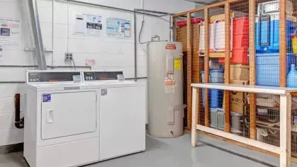A laundry area with a washer and dryer, along with storage shelves and a water heater.