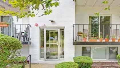 A close-up view of an apartment entrance surrounded by balconies adorned with potted plants.