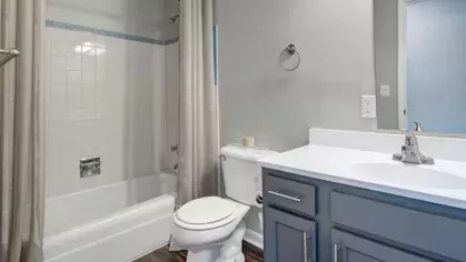 A clean, modern bathroom with a tiled shower, white vanity, and light gray walls.