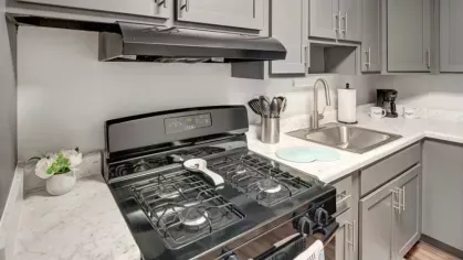 A close-up view of a kitchen showcasing a black gas stove and a marble countertop.