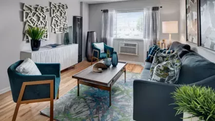 A modern living room with a blue sofa, patterned pillows, and contemporary decor elements.