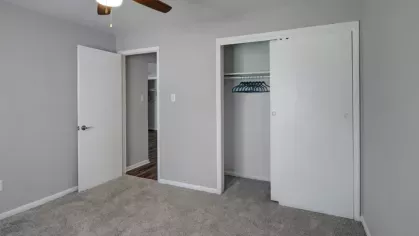 A bedroom showcasing an open closet with sliding doors and a ceiling fan.