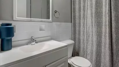 A bathroom with a white vanity, tiled walls, and a shower curtain.
