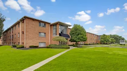 A side angle of the apartment complex highlighting the expansive lawn and walkway.