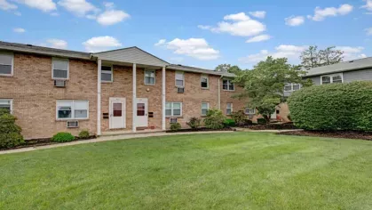 A brick apartment building with a landscaped courtyard and accessible entryways.