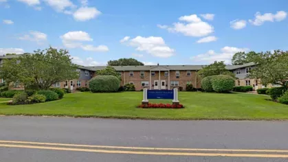 A residential building at Evergreen Village with a large green lawn and a central sign.