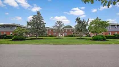A clear street view of a lush courtyard surrounded by multi-unit residential buildings.
