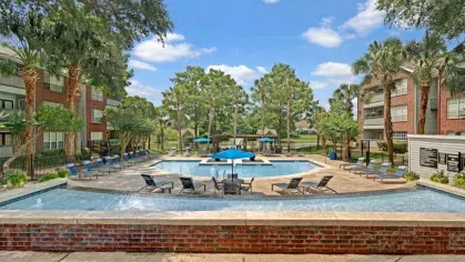 Circular pool with additional seating areas, lush landscaping, and tall palm trees in a serene setting.
