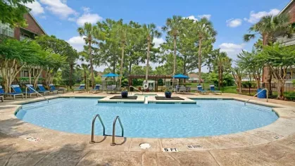 Colorful playground with a slide and climbing structures, surrounded by residential apartment buildings.