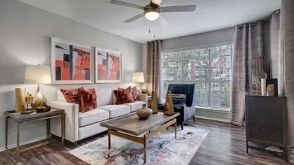 A spacious living room featuring large windows, colorful decor, and a cozy seating arrangement.