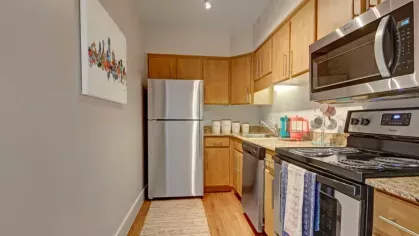 A compact kitchen with wooden cabinetry, granite countertops, and stainless steel appliances.