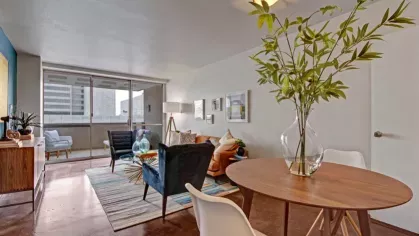 A stylish living room with a vibrant blue accent wall, a tan couch, and eclectic decor.