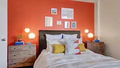 A cozy bedroom with a vibrant orange accent wall and stylish decor.