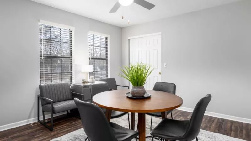A cozy dining room with a round table and sleek black chairs in front of bright windows.