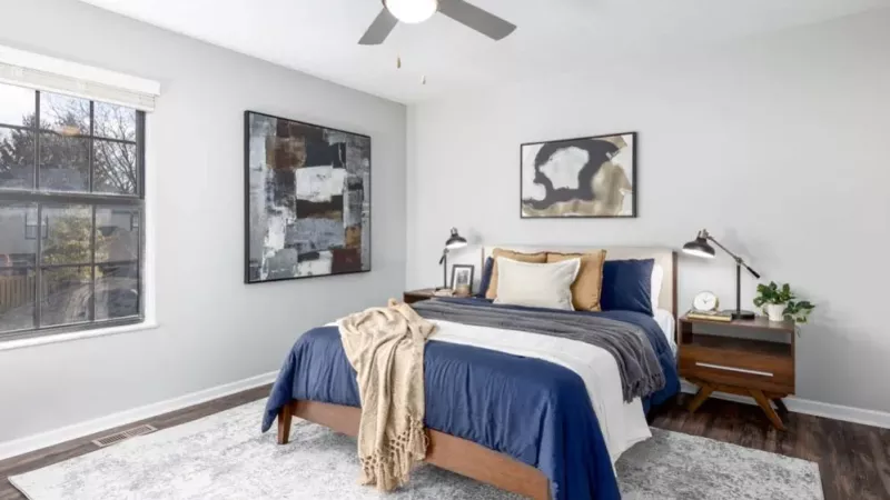 A serene bedroom with a blue-and-gray theme, a large window, and modern wall art.